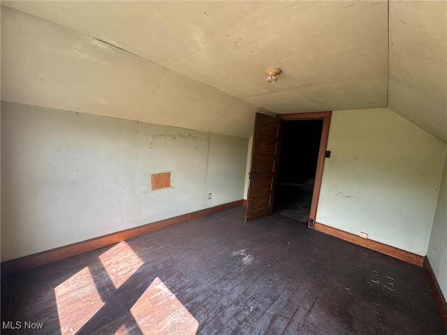 additional living space with vaulted ceiling and dark hardwood / wood-style floors