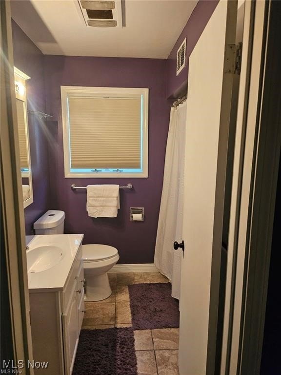 bathroom with a shower with curtain, vanity, toilet, and tile patterned floors