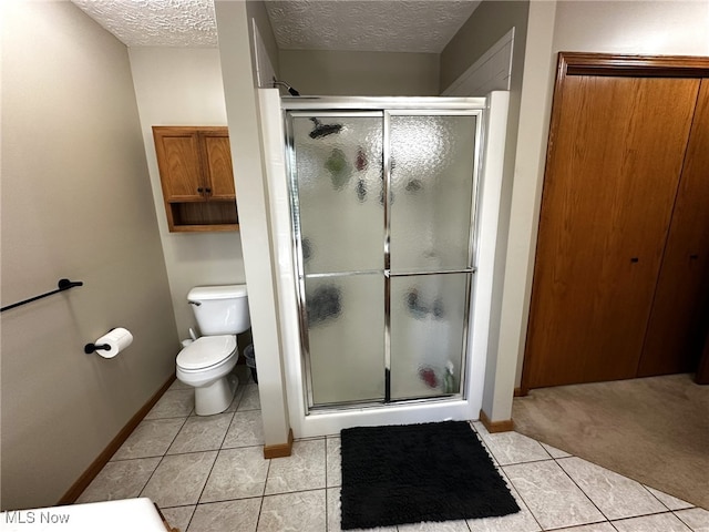 bathroom featuring a textured ceiling, tile patterned flooring, toilet, and a shower with shower door