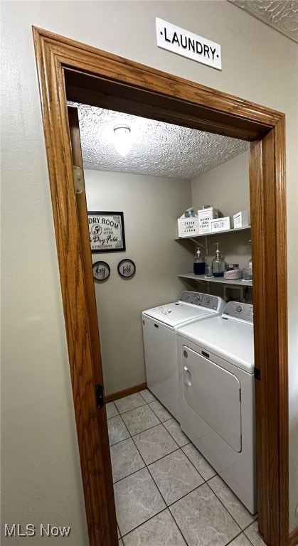 laundry room featuring a textured ceiling, light tile patterned floors, and independent washer and dryer