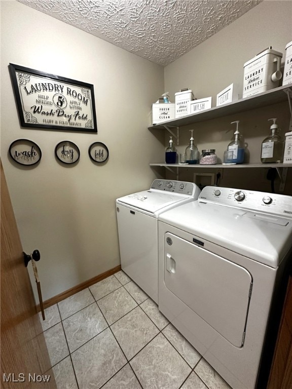 laundry room with a textured ceiling, light tile patterned floors, and washing machine and dryer