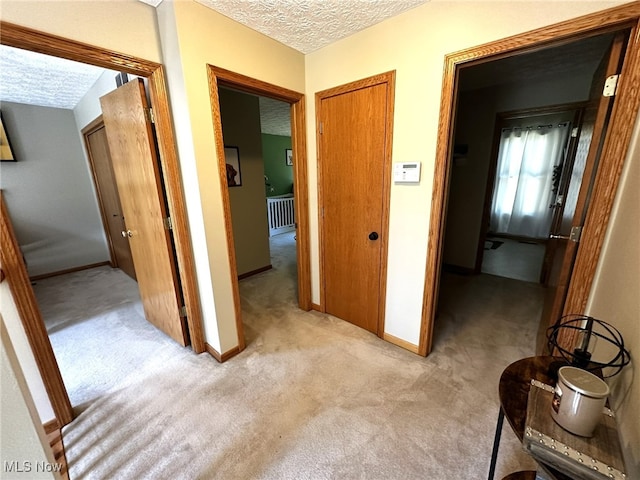 corridor featuring light carpet and a textured ceiling