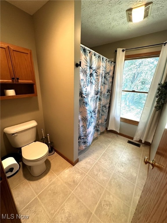 bathroom featuring tile patterned flooring, a textured ceiling, and toilet