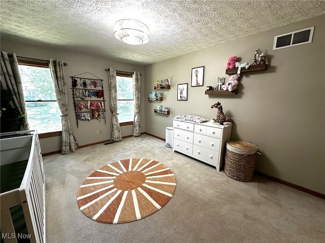 unfurnished bedroom with light carpet, a textured ceiling, and multiple windows