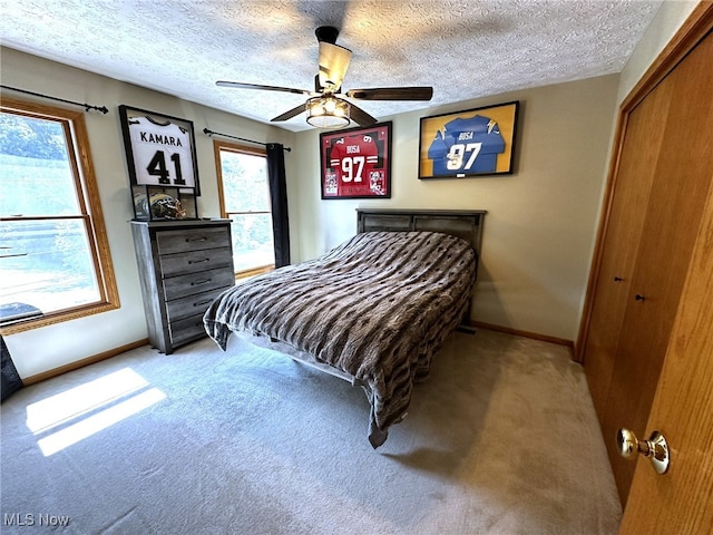 carpeted bedroom with a textured ceiling, ceiling fan, and a closet