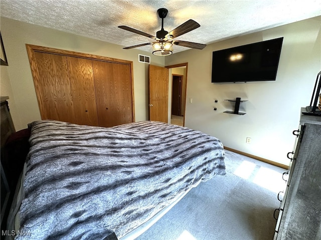 bedroom featuring a textured ceiling, carpet flooring, ceiling fan, and a closet