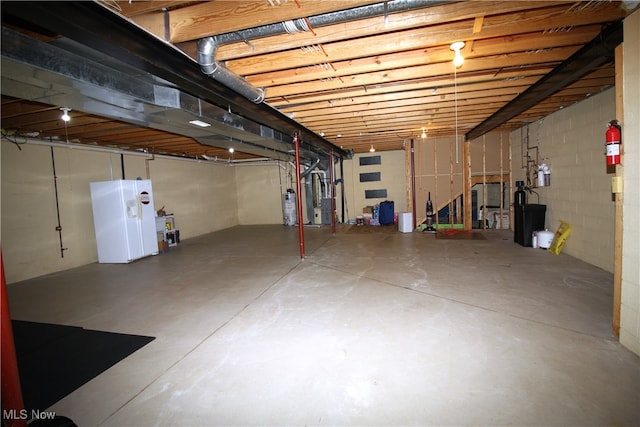 basement featuring white fridge with ice dispenser and water heater