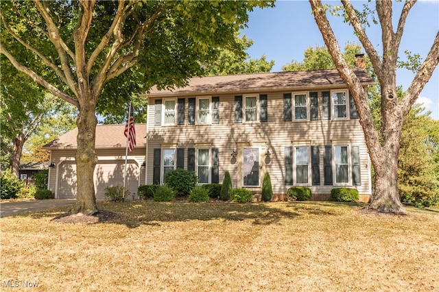 colonial home featuring a front yard and a garage