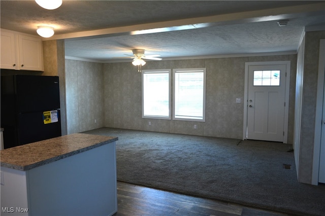 kitchen featuring white cabinetry, dark hardwood / wood-style flooring, a textured ceiling, ceiling fan, and black fridge