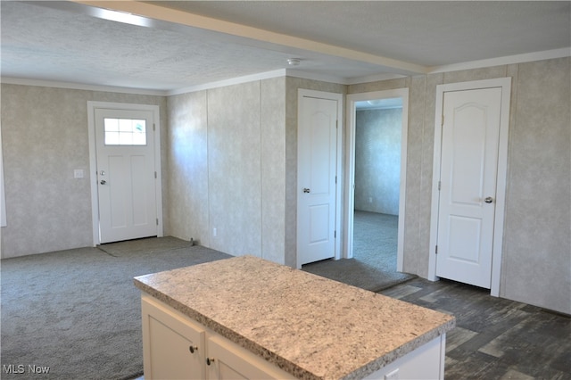 kitchen featuring white cabinets, a textured ceiling, crown molding, a center island, and dark hardwood / wood-style floors