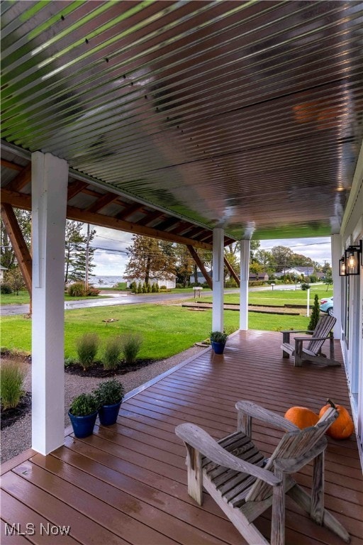 wooden deck featuring covered porch and a lawn