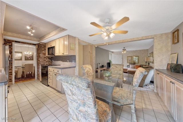 kitchen featuring light tile patterned floors, backsplash, black appliances, ceiling fan with notable chandelier, and a raised ceiling