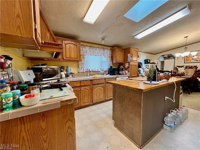 kitchen featuring a textured ceiling, a center island, sink, a skylight, and decorative light fixtures