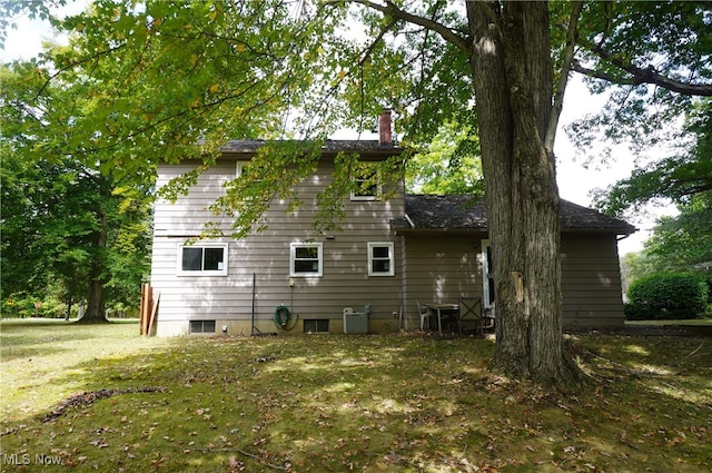 back of house with a lawn and central air condition unit