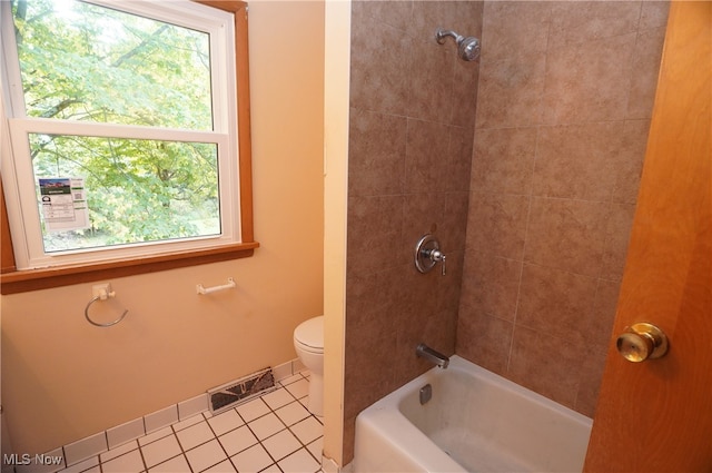 bathroom with tile patterned flooring, tiled shower / bath combo, toilet, and a wealth of natural light