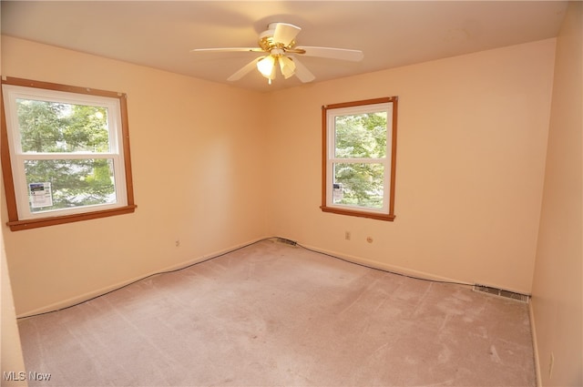 unfurnished room with a wealth of natural light, ceiling fan, and light colored carpet