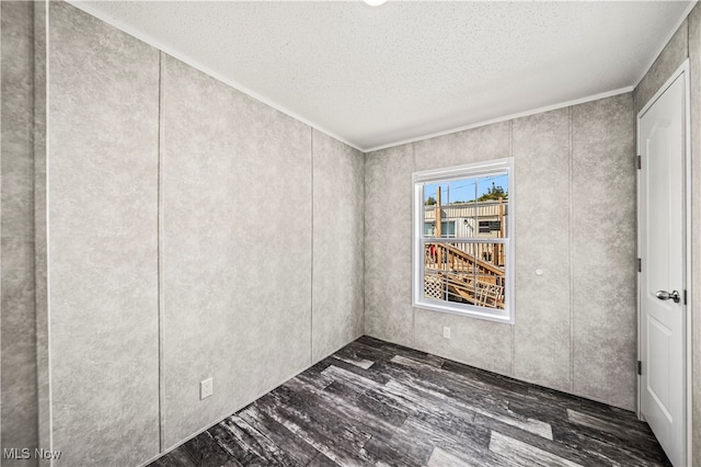 unfurnished room with a textured ceiling, crown molding, and dark wood-type flooring