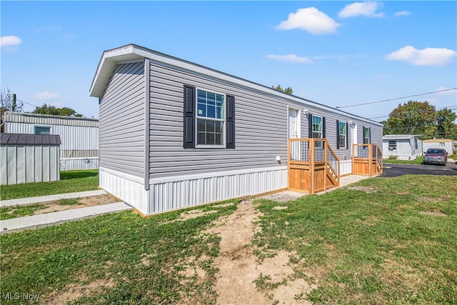 manufactured / mobile home featuring a front yard and a shed