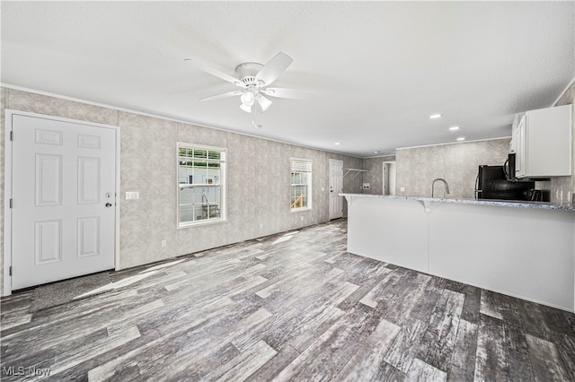 kitchen with light stone counters, hardwood / wood-style flooring, white cabinetry, kitchen peninsula, and ceiling fan