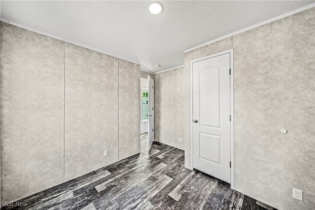 unfurnished bedroom with ornamental molding, a textured ceiling, and dark hardwood / wood-style floors