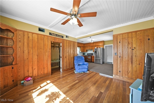 unfurnished living room featuring ceiling fan, wood walls, crown molding, and hardwood / wood-style floors