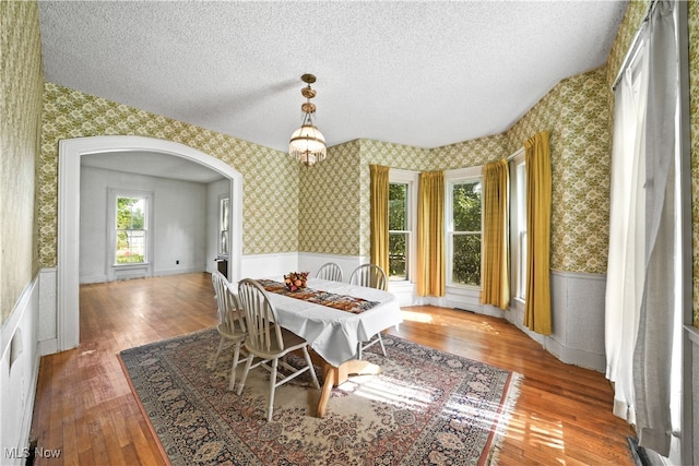 dining room with a textured ceiling, vaulted ceiling, hardwood / wood-style floors, and a notable chandelier