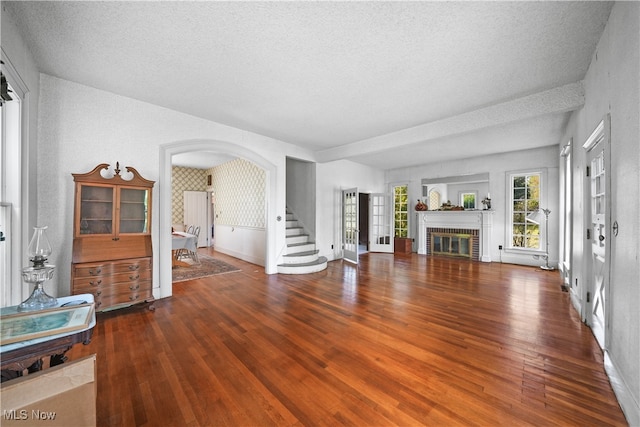 living room with a brick fireplace, a textured ceiling, and hardwood / wood-style floors