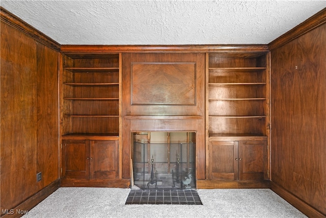 unfurnished living room featuring light carpet, a textured ceiling, and wooden walls