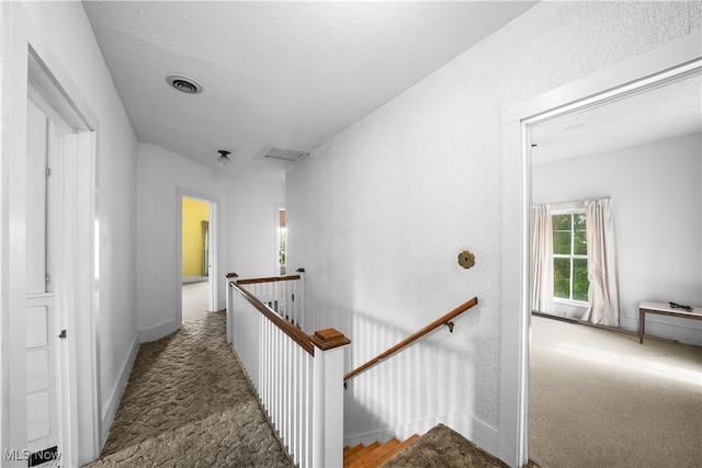 corridor with carpet floors and a textured ceiling