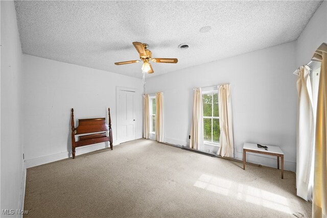 unfurnished room featuring a textured ceiling, carpet, and ceiling fan