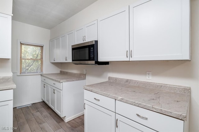 kitchen featuring light stone countertops, white cabinetry, and light hardwood / wood-style floors