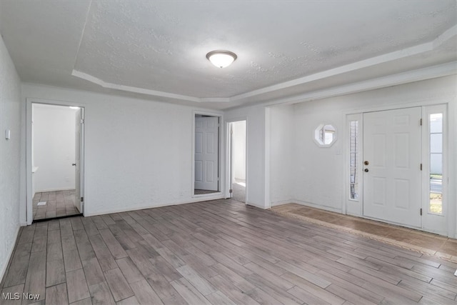 entryway with light hardwood / wood-style flooring, a tray ceiling, and a textured ceiling