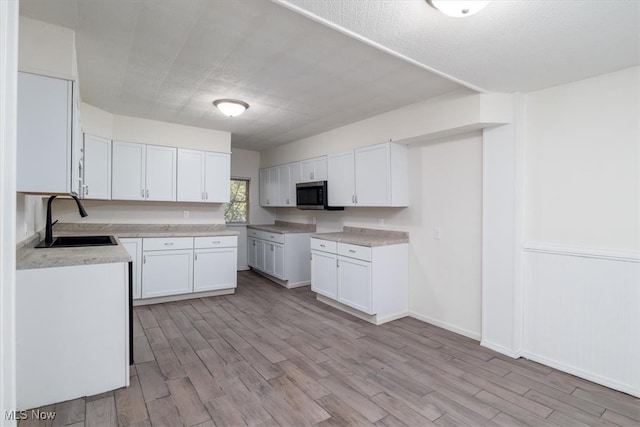 kitchen featuring light wood-type flooring, sink, and white cabinetry