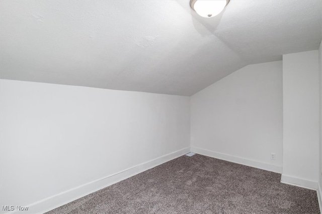 bonus room featuring carpet, lofted ceiling, and a textured ceiling