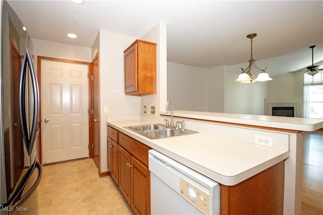 kitchen featuring stainless steel refrigerator, ceiling fan with notable chandelier, kitchen peninsula, dishwasher, and sink