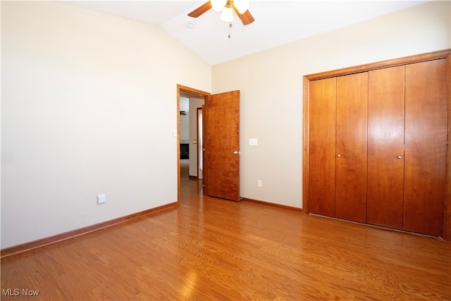 unfurnished bedroom featuring light hardwood / wood-style floors, vaulted ceiling, ceiling fan, and a closet