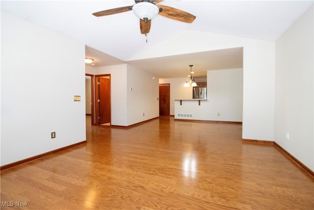 interior space with ceiling fan with notable chandelier, light wood-type flooring, and vaulted ceiling