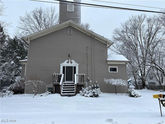 snow covered property featuring a chimney