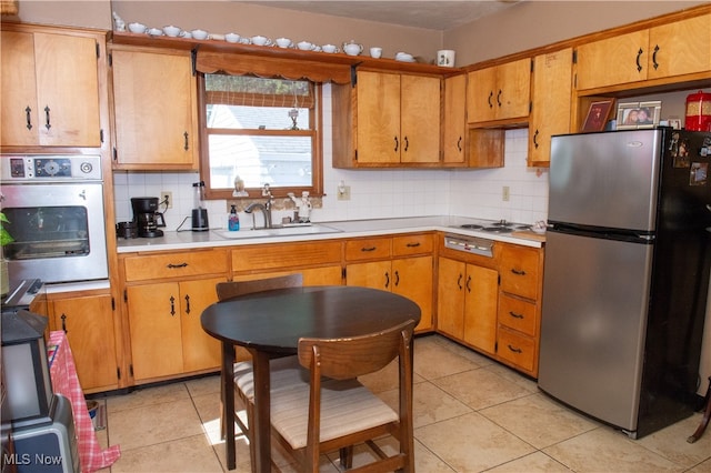 kitchen with light tile patterned flooring, stainless steel appliances, backsplash, and sink