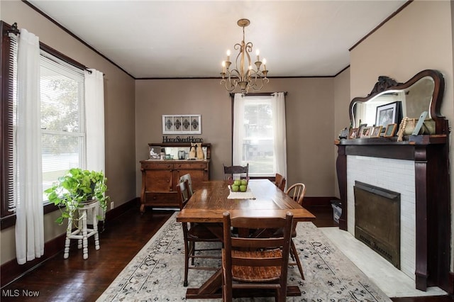 dining space with crown molding, a fireplace, dark wood-type flooring, and a notable chandelier