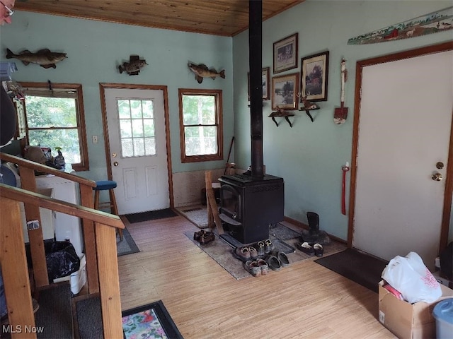 entryway featuring hardwood / wood-style floors, wooden ceiling, and a wood stove