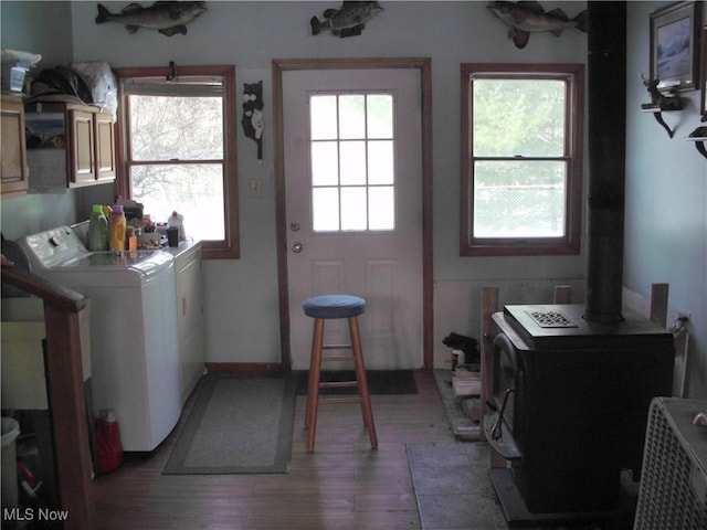 clothes washing area featuring independent washer and dryer, light wood-type flooring, cabinets, and a wood stove