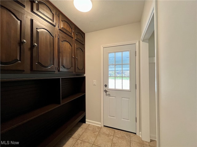 doorway to outside with a textured ceiling and light tile patterned flooring