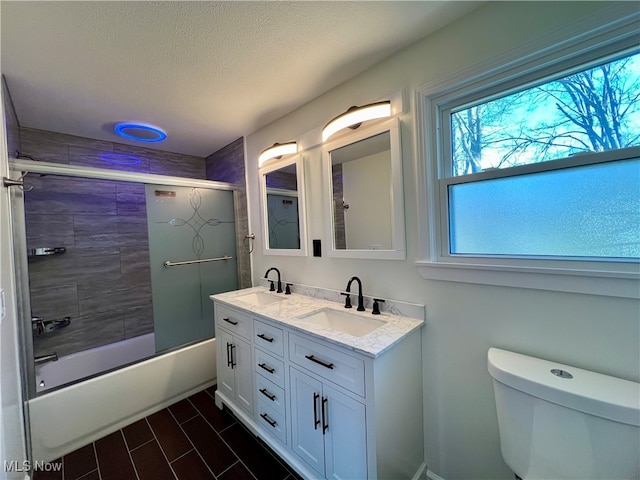 full bathroom with combined bath / shower with glass door, vanity, and toilet