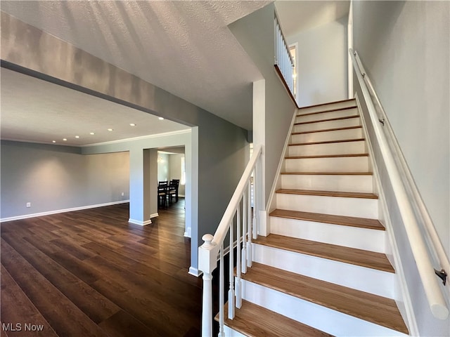 stairway with wood-type flooring and a textured ceiling