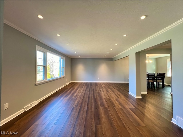 empty room with an inviting chandelier, dark hardwood / wood-style floors, and crown molding