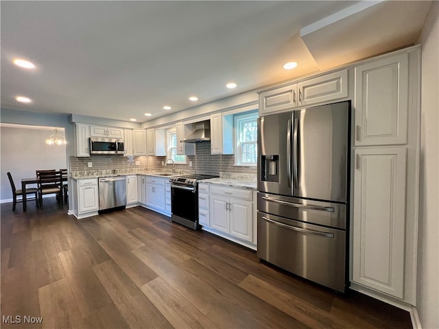 kitchen with dark wood-type flooring, white cabinets, light stone countertops, stainless steel appliances, and sink