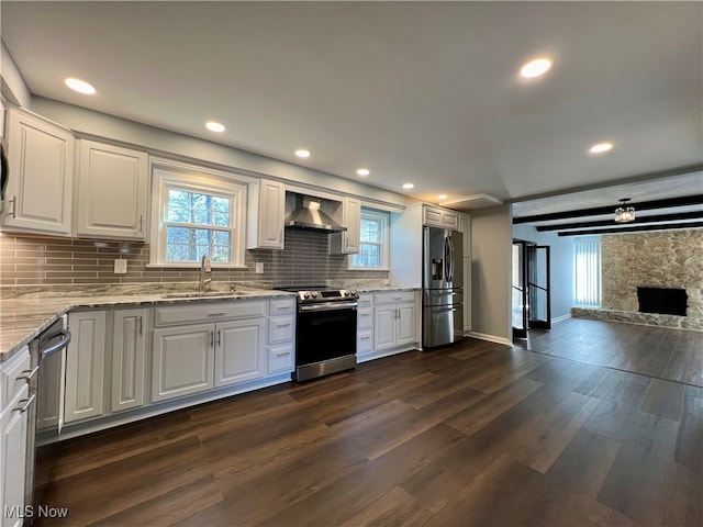 kitchen featuring appliances with stainless steel finishes, white cabinetry, tasteful backsplash, dark hardwood / wood-style floors, and wall chimney range hood