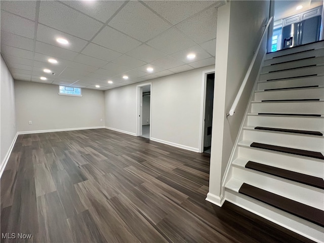 basement with a drop ceiling and dark hardwood / wood-style floors