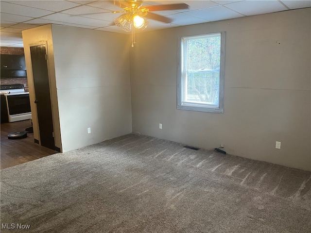 empty room featuring ceiling fan, a paneled ceiling, and dark wood-type flooring